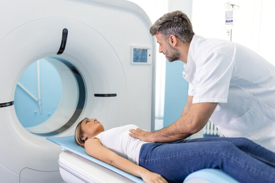 The patient lies on CT or MRI, the bed is moved inside the machine, scanning her body and brain under the supervision of a doctor, radiologist. In a medical laboratory with high-tech equipment.