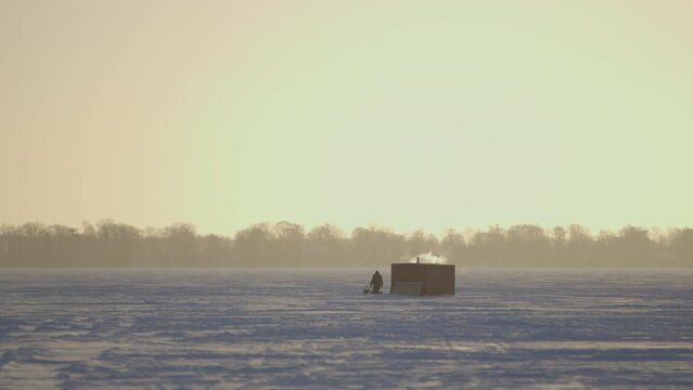 Barn, building in a snowy rural area against a skyline of trees behind fog