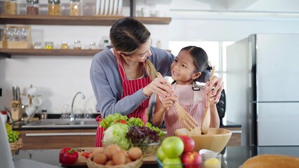 Asian mother and daughter cooking together in kitchen are preparing healthy food. Happy Asian family making salad enjoy family activity together
