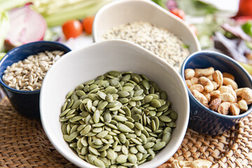 Close-up, a bowl of pumpkin seeds and other healthy foods on the kitchen table.