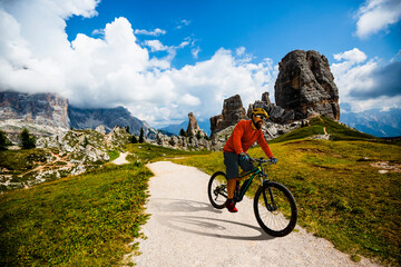 A man ride electric mountain bikes in the Dolomites in Italy. Mountain biking adventure on beautiful mountain trails.
