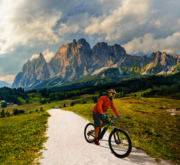 Naklejka na ściany i meble A man ride electric mountain bikes in the Dolomites in Italy. Mountain biking adventure on beautiful mountain trails.