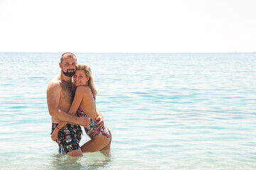 Happy lovely couple together hugging in azure sea water, summer vacation. Young family couple woman and man looking at camera enjoy honeymoon on seaside. Travel holidays concept. Copy ad text space