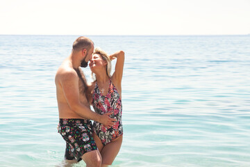 Happy family couple together kissing in azure sea water, summer vacation. Young lovely couple woman and man looking at camera enjoy honeymoon on seaside. Travel holidays concept. Copy ad text space