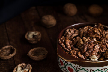 Bowl with organic dried walnuts on a dark wooden background. Healthy fod concept.