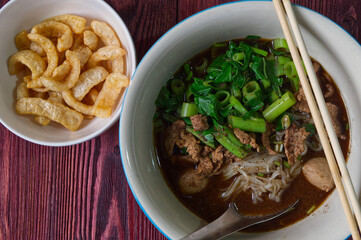 Beef Boat Noodles with Pork Blood Soup, Delicious Asian Style Noodle Serving with Pork Rind on the Wood Table.