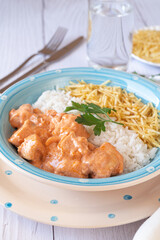 Close-up of Chicken strogonoff with rice and potato straw on white wooden table. Brazilian cuisine.