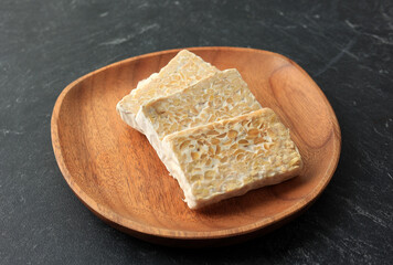 Sliced Raw Tempe or Tempeh on Wooden Plate.