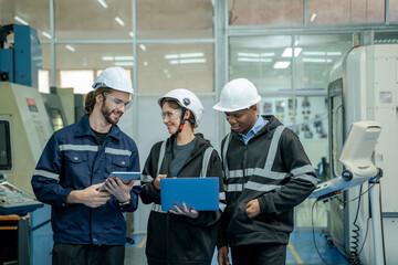 Engineer using laptop computer controlling automated robot hand with CNC machine in smart factory.