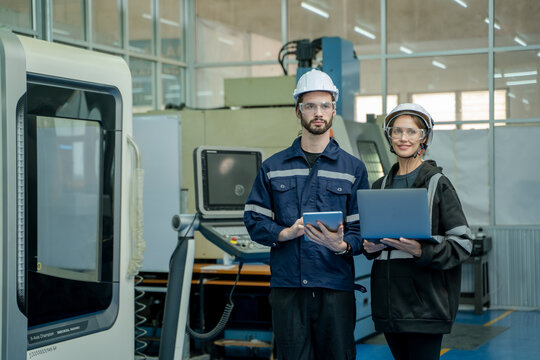 Engineer using laptop for programming modern robot arm in automated manufacturing industry,Factory worker with responsibility for programming industrial machine to control the process of production.