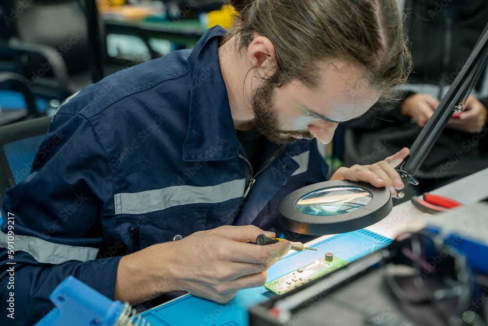 Poster electrical worker working with circuit board,repairing electronic device on the circuit board.