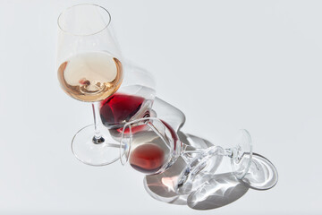 Top view of three glasses filled with delicious red and wine, standing, lying against white background with reflected lights. Concept of taste, alcohol, wine degustation, variety, winemaking. Flat lay