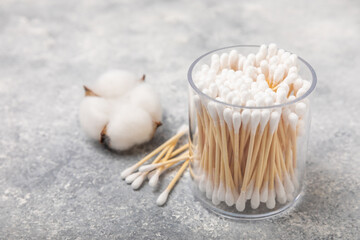 Cotton swabs in craft packaging and holder on a gray cement background. Bamboo cotton buds. Means for hygiene of ears. Eco-friendly materials.Hygienic cotton ear buds.