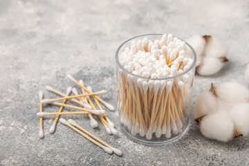 Cotton swabs in craft packaging and holder on a gray cement background. Bamboo cotton buds. Means for hygiene of ears. Eco-friendly materials.Hygienic cotton ear buds.