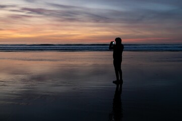 a person standing on top of a wet beach next to the ocean