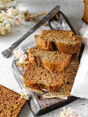 Vertical shot of banana bread on wood with a knife next to it