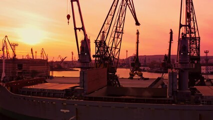 Black Sea Grain Initiative 2023 grain Deal. Silhouettes of port cranes during the loading of grain on a bulk carrier at sunset during the golden hour. Panoramic flight from a drone