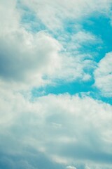 Obraz premium Vertical shot of white dense fluffy clouds in the blue sky