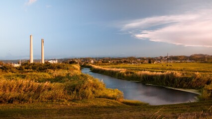 Obraz premium Scenic view of a narrow river flowing amid the fields under the blue sky