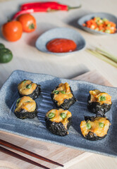 Steamed dimsum served on plate with chili, tomato and sauce as background on wooden table