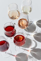 Traditional taste. Glasses filled with different white, rose and red wine standing against white...