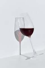 Glass filled with delicious, high quality red wine, standing near wall against white background. Traditional taste. Concept of taste, alcohol, wine degustation, variety, winemaking. Flat lay