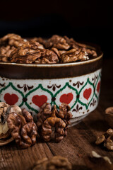 Bowl with dried walnut kernels on a dark rustic table.