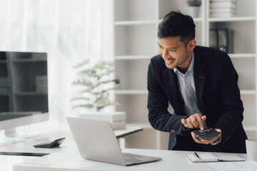 Fototapeta premium Happy working asian businessman talking on the phone with accounting documents at desk in happy working office