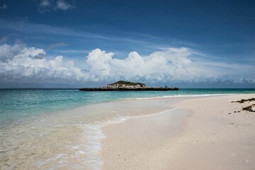 Sandy beach and the calm sea with a small island In the background in Okinawa, Japan