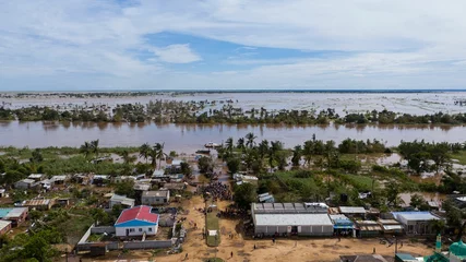 Rolgordijnen Big flood with trees and a village in the dirty waters in Africa © Bruno Pedro/Wirestock Creators