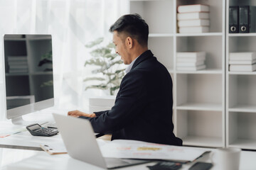 Fototapeta premium Happy working asian businessman talking on the phone with accounting documents at desk in happy working office