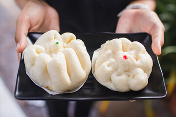Chinese traditional steamed bun (Bakpao), served on plate with women hand 