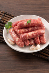 Raw Taiwanese sausage in garlic flavor in a plate on wooden table background.
