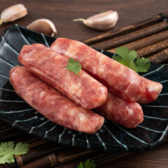 Raw Taiwanese sausage in garlic flavor in a plate on wooden table background.
