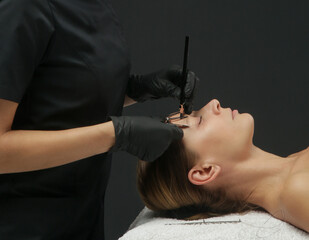 Mikrobleiding eyebrow measurement. Cosmetologist makes markings with pencil and threads for perfect...