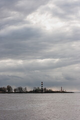 Dramatic view with overcast sky of a white ship warning beacon built on an island.