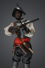 Fototapeta premium Shot of medieval soldier dressed in steel armor and helmet aiming flintlock musket.