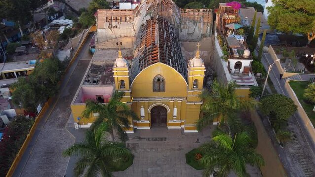 Old closed down church with a crumbling roof called "Iglesia La Ermita" Drone flies back and up revealing in the background the pacific ocean. Located in Barranco district of Lima, Peru.
