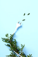 Power plug wrapped green leaves on blue background. Ecology, Environmental conversation, green energy concept.