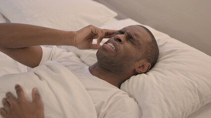 Fototapeta na wymiar African Man with Headache Lying in Bed 