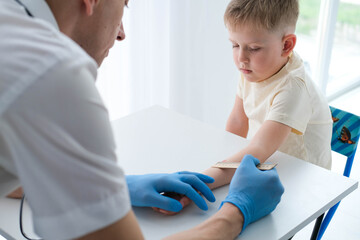 A male doctor makes an important Mantoux test on a child. The doctor measures the Mantoux test with a ruler for a little boy