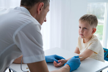 Fototapeta premium A male doctor makes an important Mantoux test on a child. The doctor measures the Mantoux test with a ruler for a little boy