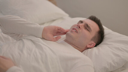 Young Man with Toothache Lying in Bed