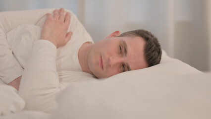 Pensive Young Man Sleeping in Bed on Side