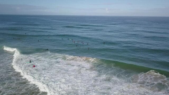 Aerial orbit surfers and bodyboarders waiting in water for next wave, sunny day