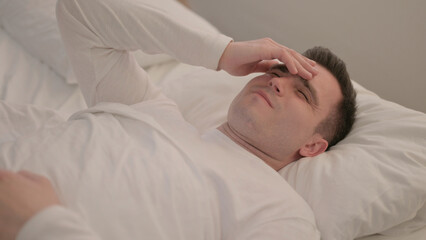 Fototapeta na wymiar Young Man with Headache Lying in Bed 