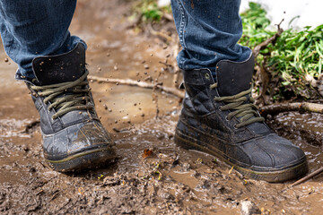 A man in jeans and boots walks through the swamp in rainy weather.