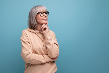 portrait of a kind grandmother with gray hair in a casual youth look on a studio background with...