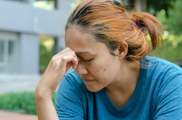 Fototapeta premium Asian women sitting at park feel a headache or dizzy, feeling tired. need painkillers