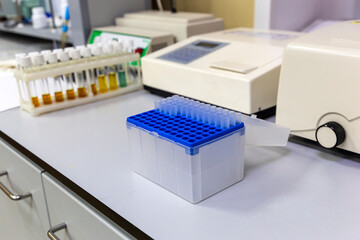 laboratory table with multi-colored reagent vials in the stand, disposable plastic test tubes and measurement machines